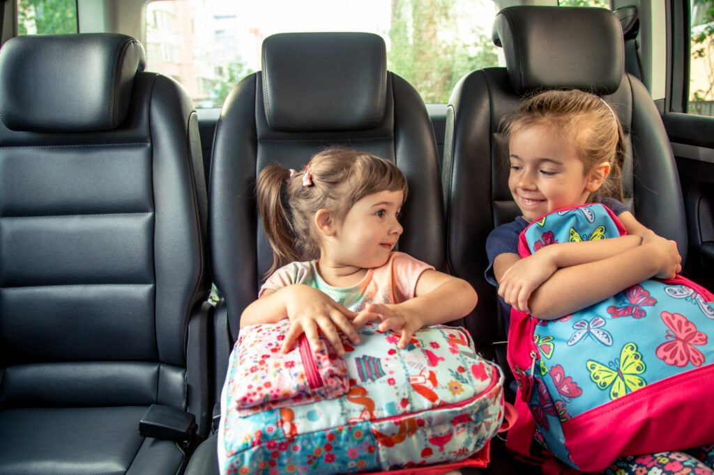 Sestry s batohy v autě na zadní sedačce